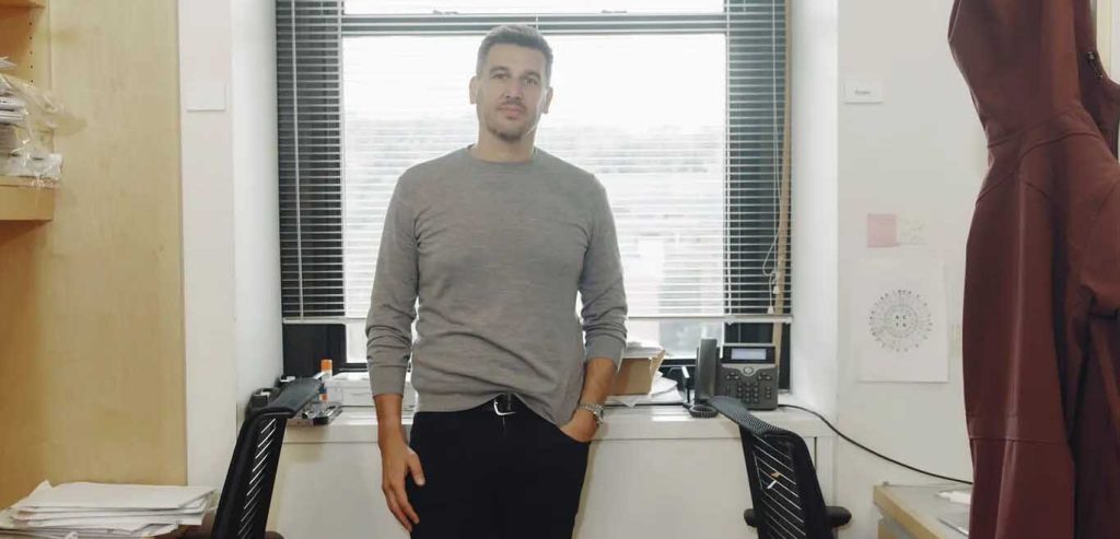 Man standing at a lab window looking at the camera.
