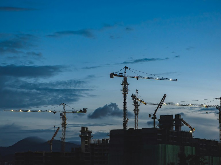 Construction cranes in front of the sky