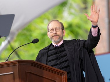 Alan Garber standing at a podium, waving to the audience.