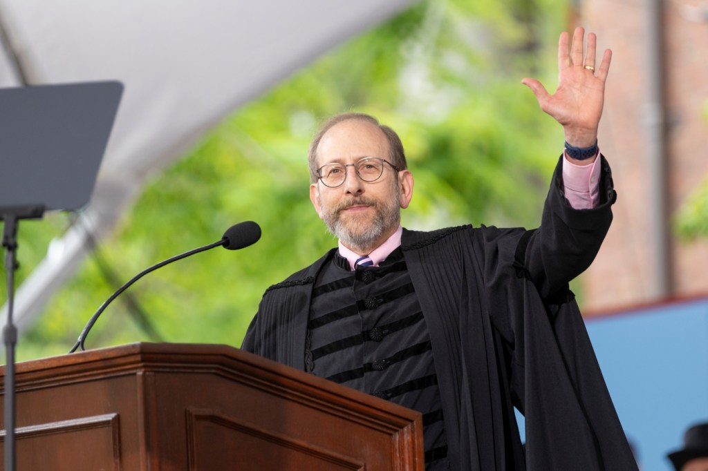Alan Garber standing at a podium, waving to the audience.