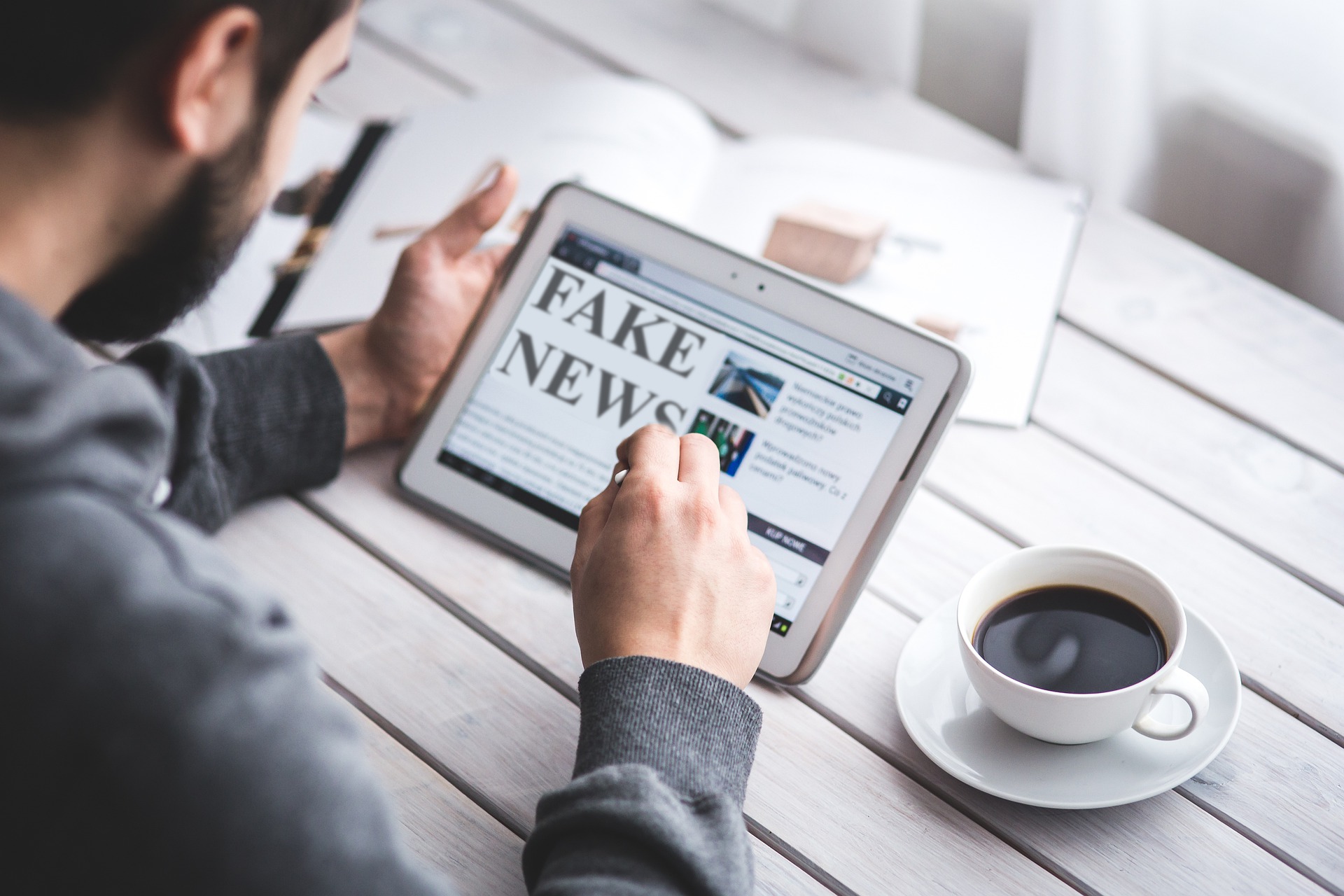 A man reading an ipad that says "Fake news"