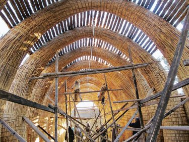 People building a large structure with natural materials