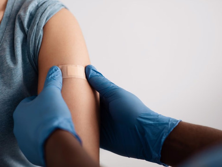 A person with a bandaid on their arm after a shot