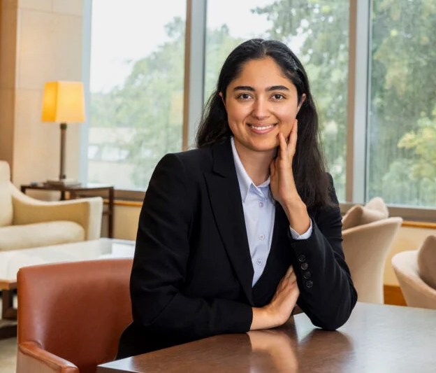 A student wearing a suit sits at a table
