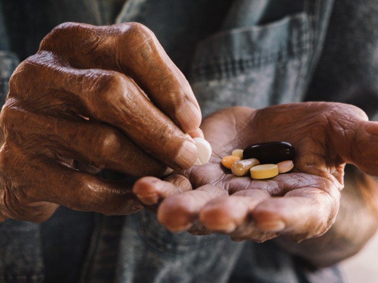 Elderly man holding vitamins in his hand