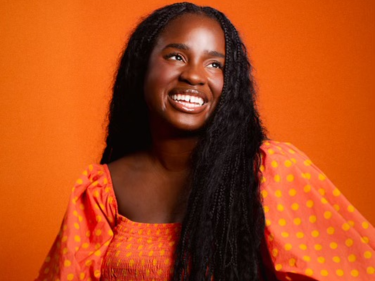 A smiling woman wearing an orange dress